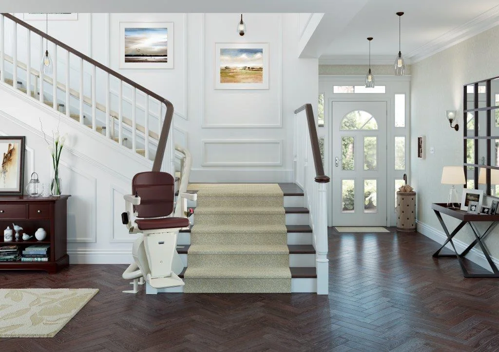curved stairlift red Modern and elegant home interior featuring a curved stairlift installed on a split staircase, with neutral-toned carpeted stairs, white railings, and stylish decor including framed artwork, pendant lighting, and a hardwood floor.