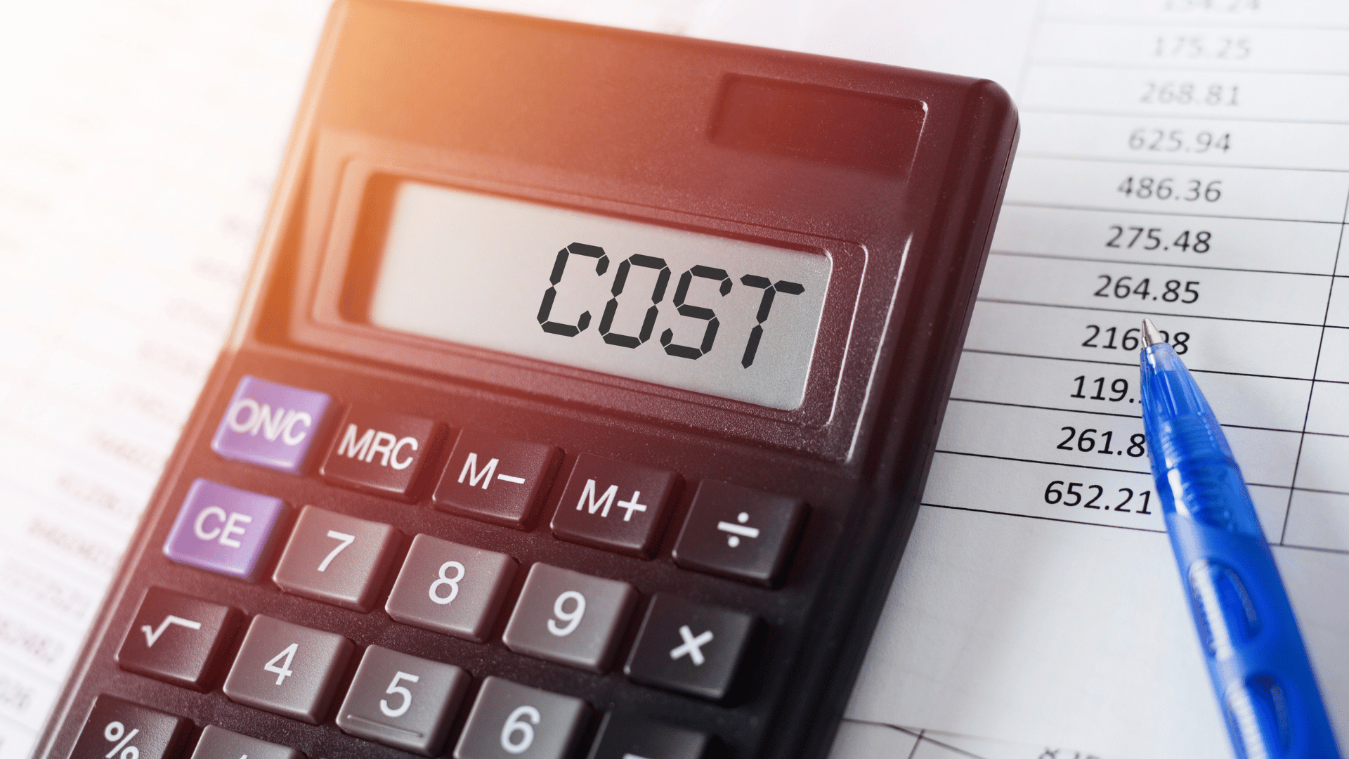 stairlift cost calcualtor Close-up of a black calculator displaying the word "COST" on its screen, placed on top of financial documents with a blue pen pointing at a column of numerical figures.