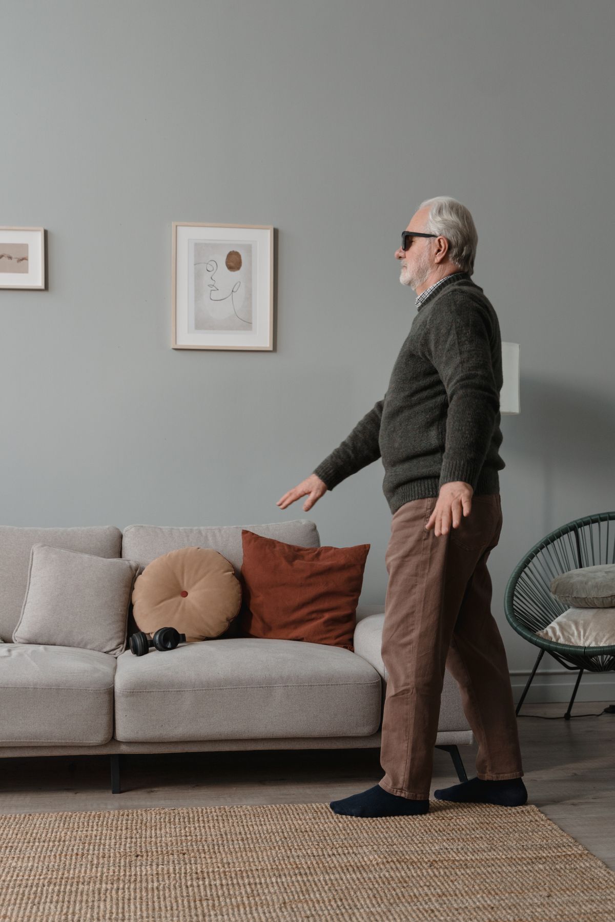 Older man in living room | Stairlift Guru Older man moving carefully around his living room