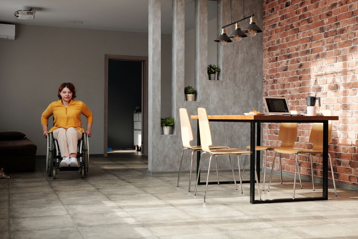 A wheelchair user in an open-plan home interior A wheelchair user in an open-plan home interior