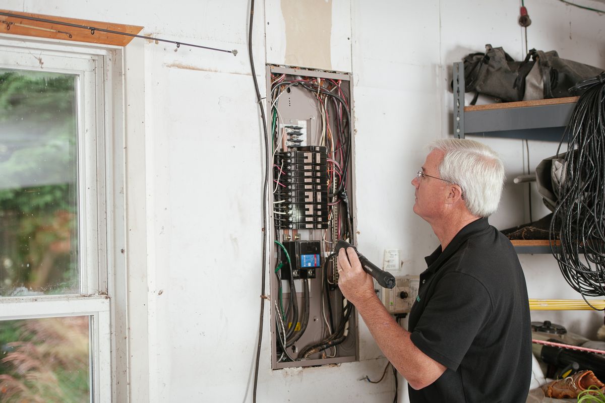 An electrician working on a fuse box in a house An electrician working on a fuse box in a house