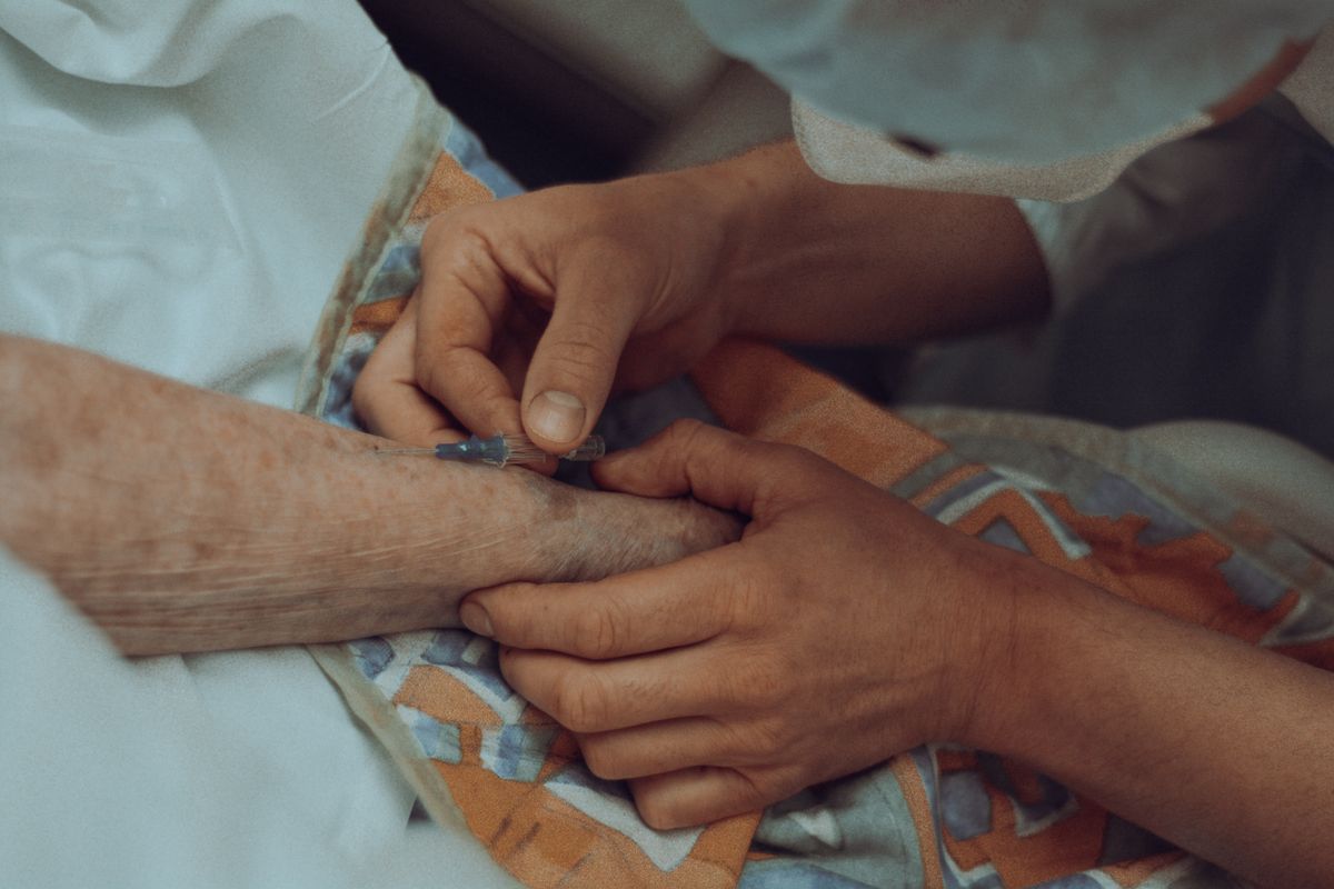 A carer holding the hand of an older patient