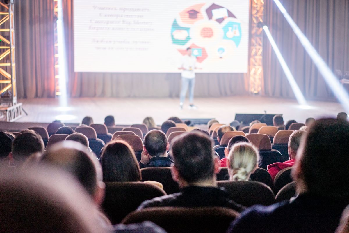 An audience watching a presentation at a conference An audience watching a presentation at a conference