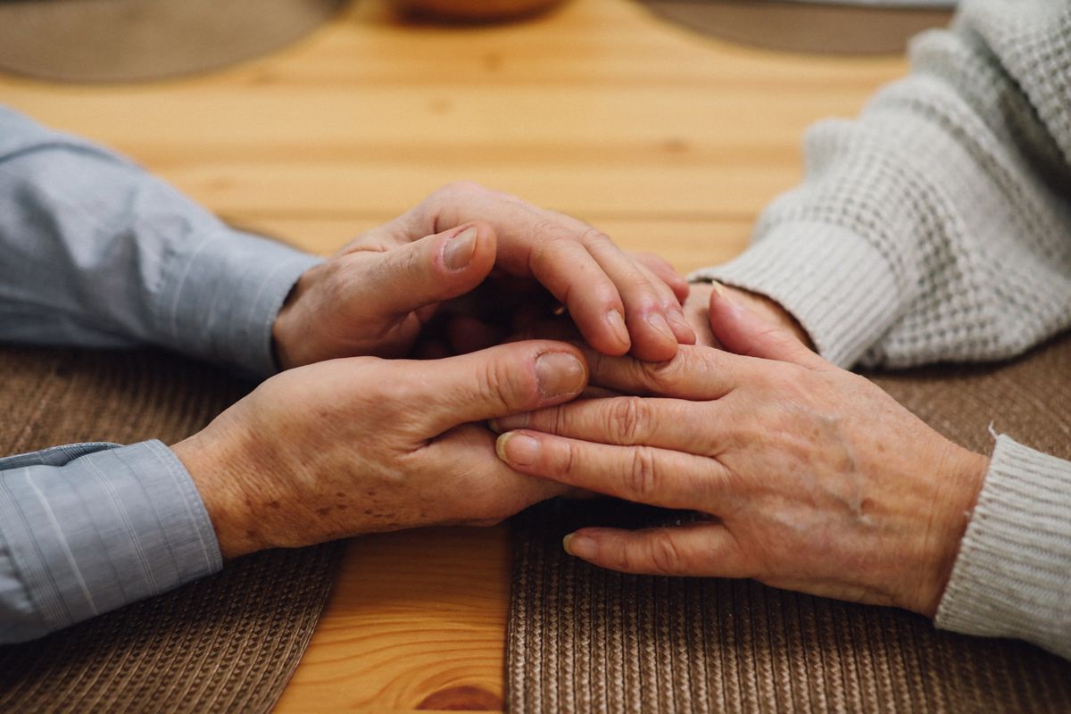 Younger hands holding the hands of an older person