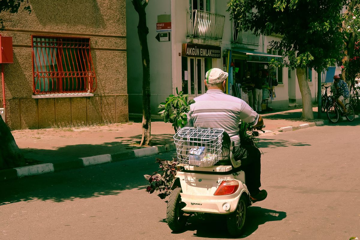 A person riding a mobility scooter along a street A person riding a mobility scooter along a street