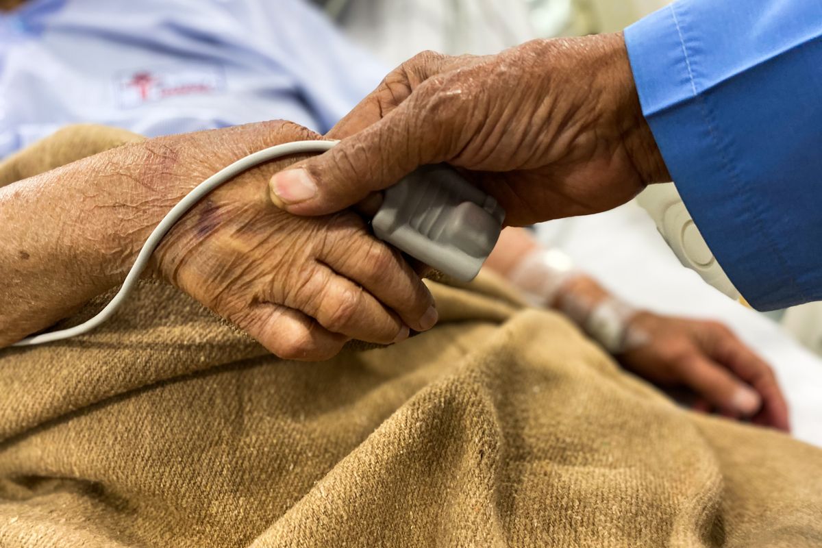 A nurse checking the hand of an older patient in hospital