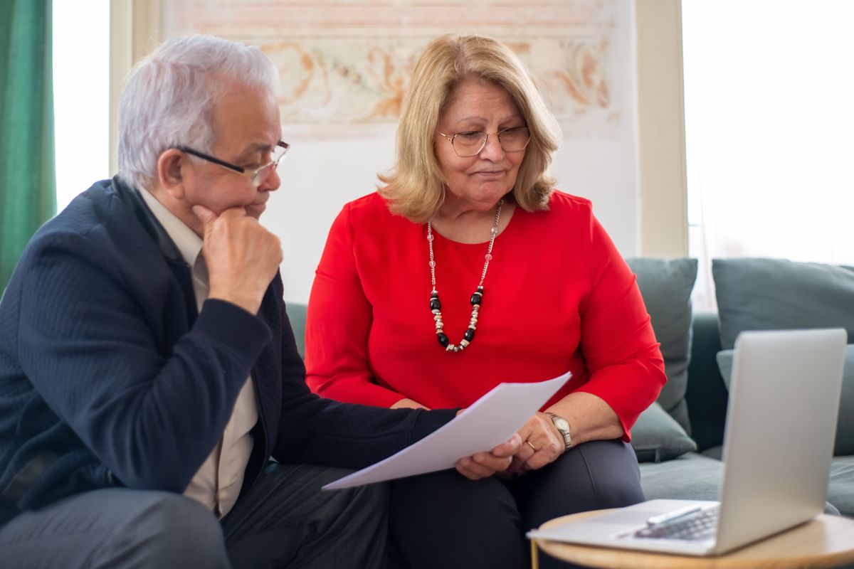 An older couple going through paperwork at home An older couple going through paperwork at home