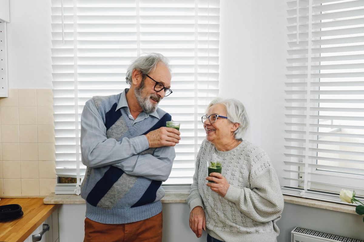 An older couple having a cup of tea in their kitchen An older couple having a cup of tea in their kitchen