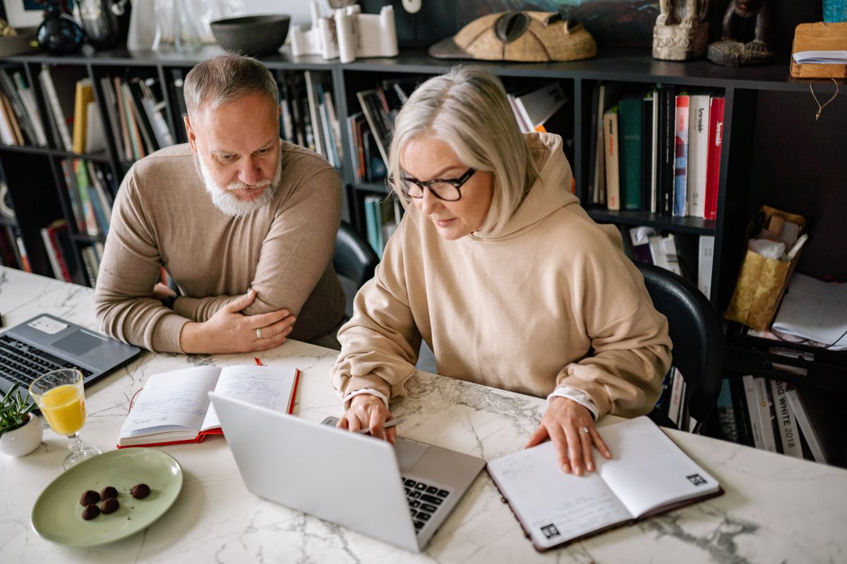 An older couple researching on a laptop at home An older couple researching on a laptop at home