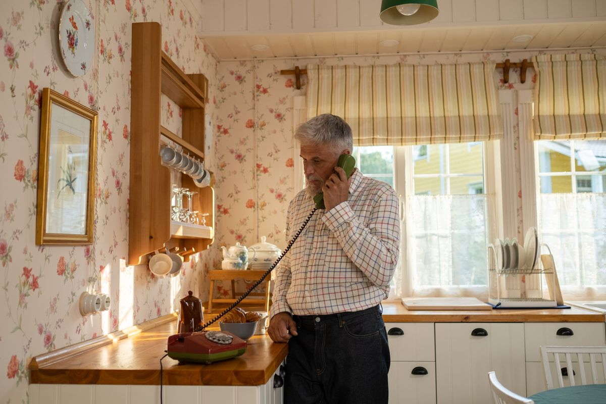 An older man using a landline telephone at home An older man using a landline telephone at home