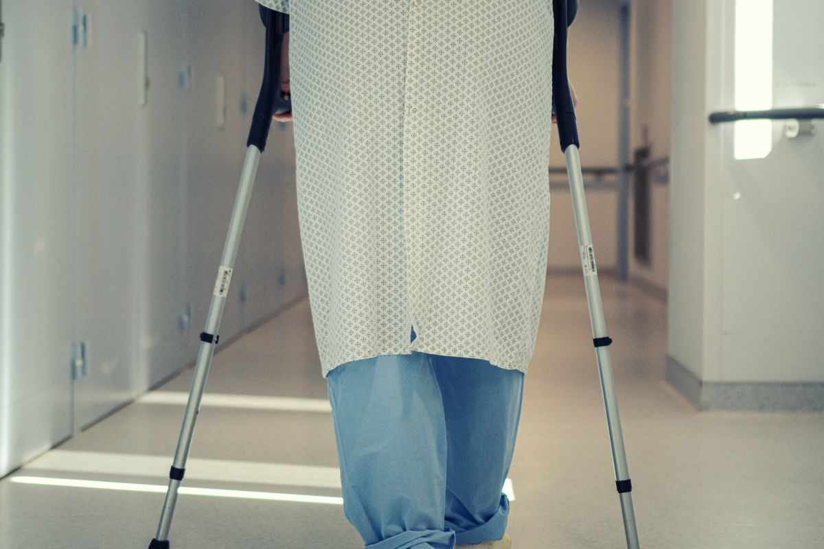 Older patient walking with crutches along a hospital corridor Older patient walking with crutches along a hospital corridor