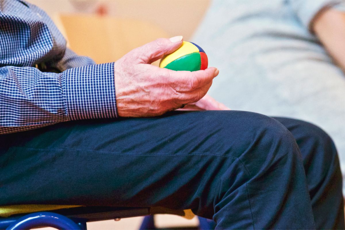 An older person squeezing a therapy ball during rehabilitation An older person squeezing a therapy ball during rehabilitation