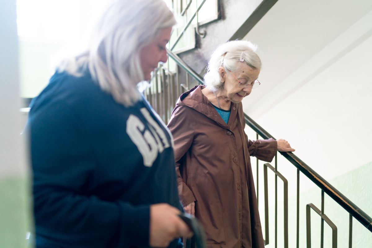 An older woman being helped down a staircase