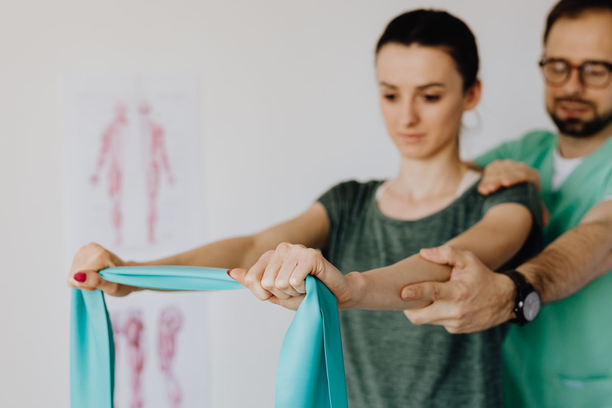 A therapist guiding a patient through a resistance band exercise A therapist guiding a patient through a resistance band exercise