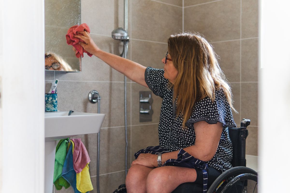 A wheelchair user in an adapted bathroom A wheelchair user in an adapted bathroom
