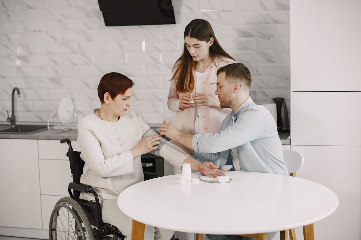 A wheelchair user talking with family at the kitchen table A wheelchair user talking with family at the kitchen table