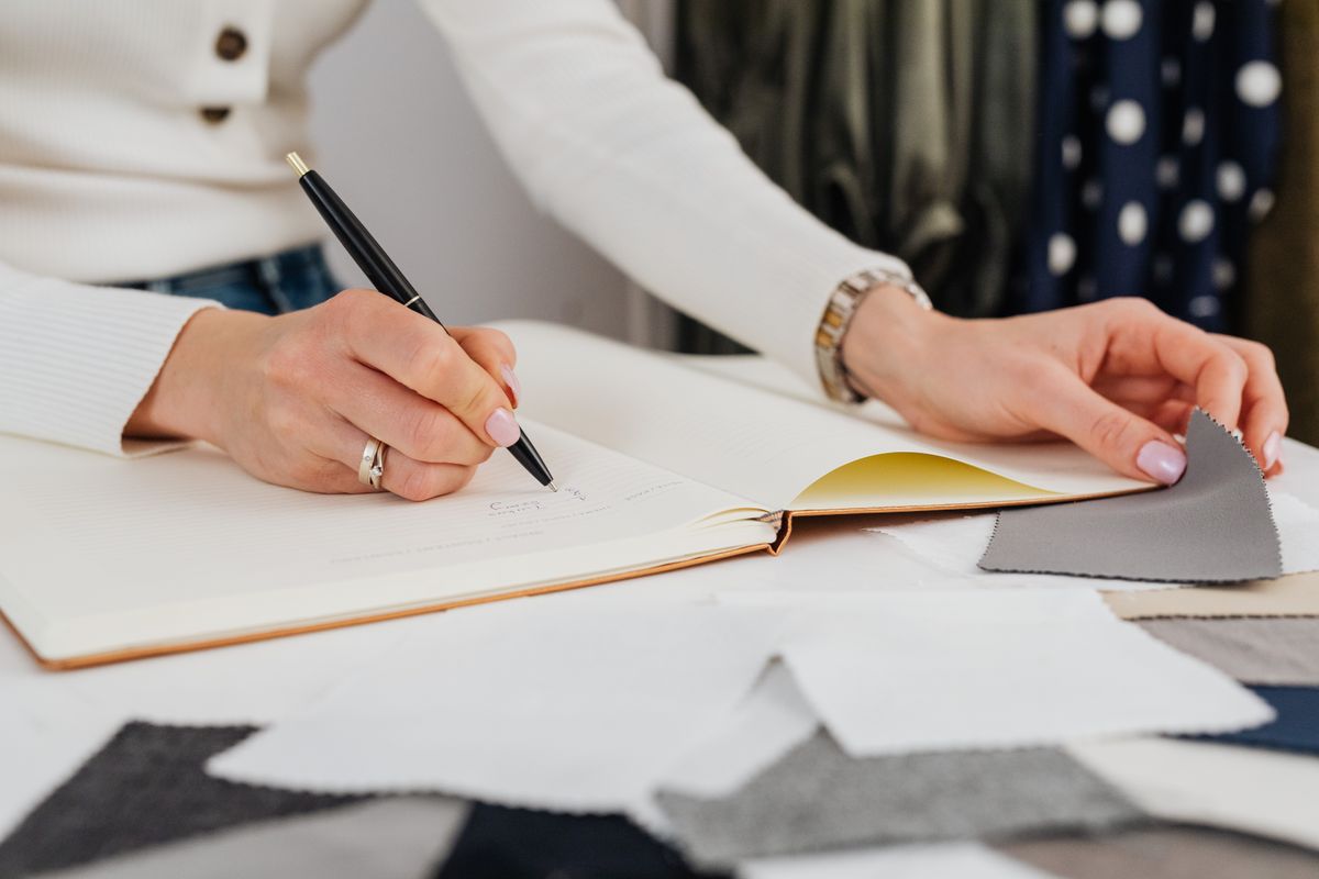 Writing in a notebook beside documents
