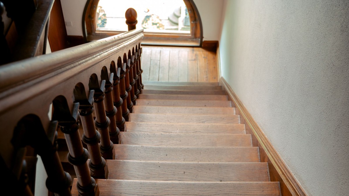 A wooden domestic staircase with a handrail, representing home adaptations for safer stairs
